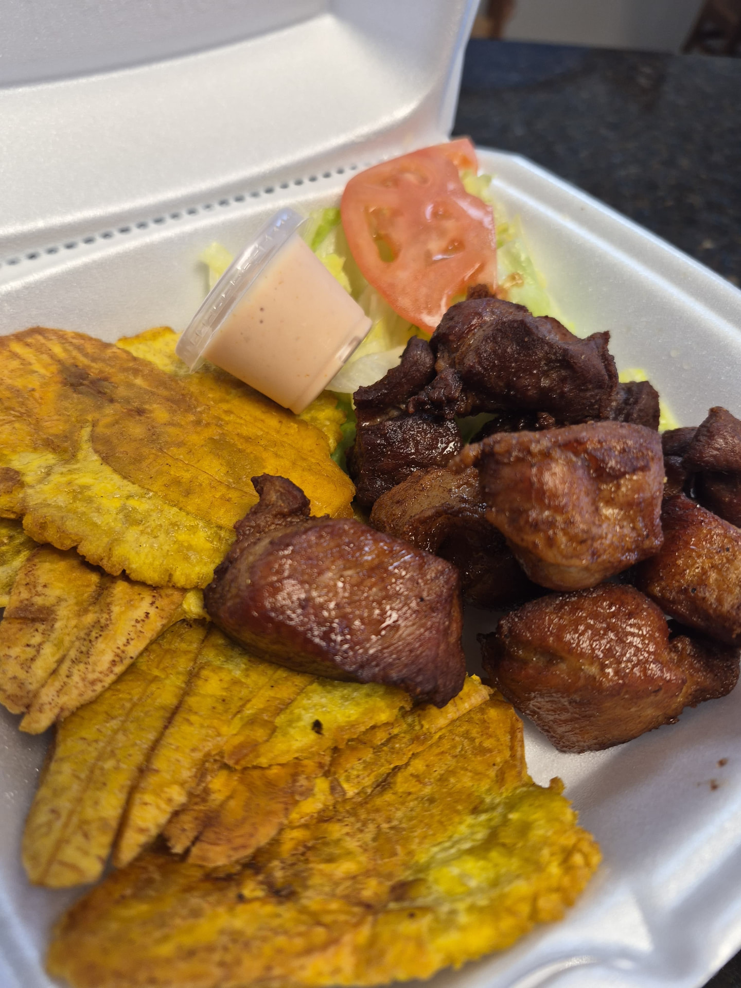 Masita de cerdo frita con tostones y ensalada